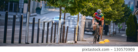 Cyclist climbing steep city street on road bike with effort and persistence. Banner 130570909