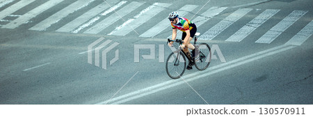 Cyclist riding road bike across city street with determination. Banner Cyclist riding road bike across city street with determination. Banner 130570911