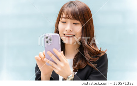 使用智慧型手機的微笑的女人/女商人 使用智慧型手機的微笑的女人/女商人 130571352