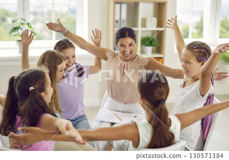Group of school children girls sitting in a circle with psychologist and raising hands up. Group of school children girls sitting in a circle with psychologist and raising hands up. 130571384