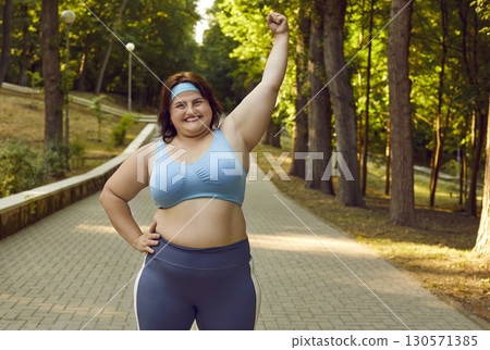 Happy chubby woman rejoicing about her success in losing weight after active sports training in park 130571385