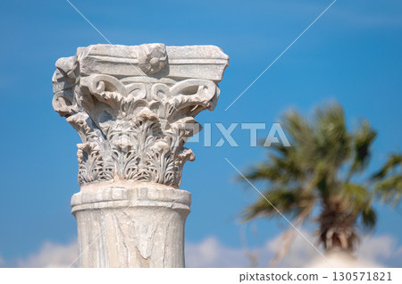 Corinthian capital of Kourion archaeological site in Cyprus with blurred palm tree and blue sky Corinthian capital of Kourion archaeological site in Cyprus with blurred palm tree and blue sky 130571821