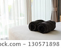 Clean back beach towel on white hotel bed with see-through curtain on background, comfort and relax. 130571898