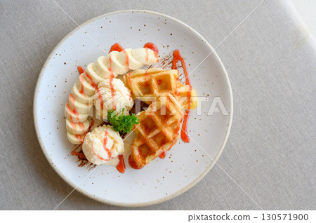 tasty dessert. Top view of Croffle serve with ice cream, banana and topping with strawberry syrup. 130571900