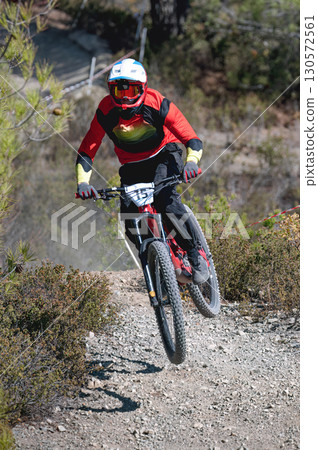 Mountain biker speeding downhill on a mountain bike, kicking up dust and navigating a rocky trail 130572561