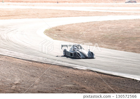 Racecar negotiating sharp desert track curve, demonstrating racing dynamics with high-velocity precision 130572566