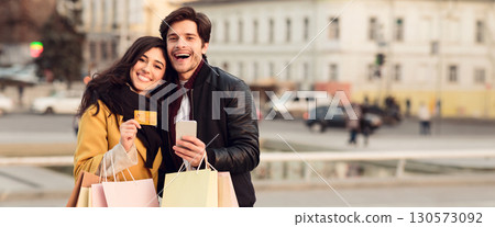 Payment and shopping online. Couple with credit card and bags outdoors, copy space, web-banner 130573092