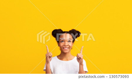 Place For Promotional Content. Smiling african teen girl pointing infex fingers up at copy space 130573093