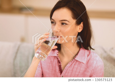 Stay Hydrated. Smiling healthy girl drinking clean mineral water from glass before breakfast, copyspace, close up 130573123