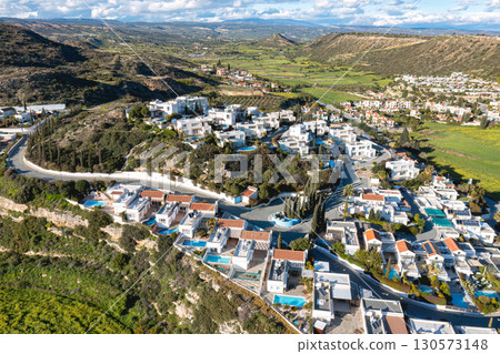 Aerial view of Pissouri village, with white houses, swimming pools, green hills, and agricultural fields, in Limassol district, Cyprus 130573148