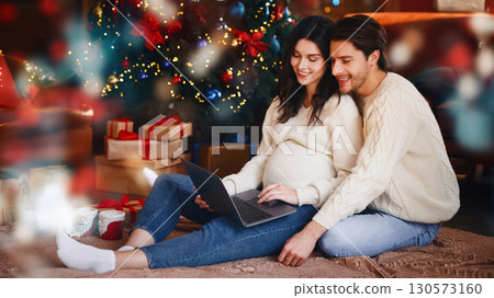 Young smiling pregnant woman and her happy husband using laptop by Christmas tree, shopping online, copy space Young smiling pregnant woman and her happy husband using laptop by Christmas tree, shopping online, copy space 130573160