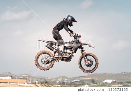 Professional motocross rider performing a jump during a race with blurred background 130573165