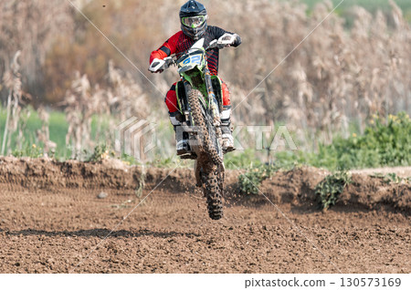 Motocross rider showing stunt skills during competition on dirt track 130573169