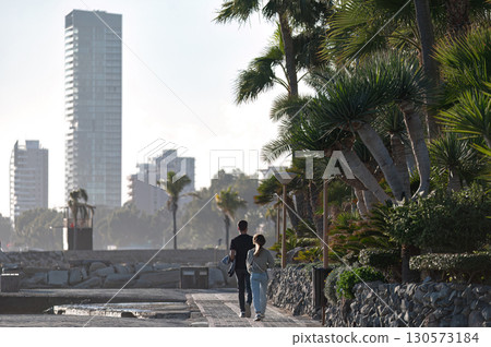 Couple walking on pavement near palm trees in Limassol, Cyprus Couple walking on pavement near palm trees in Limassol, Cyprus 130573184