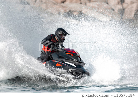Professional athlete riding a jetski at high speed on the ocean waves 130573194