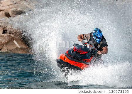 Professional athlete riding a jet ski at high speed on the sea Professional athlete riding a jet ski at high speed on the sea 130573195