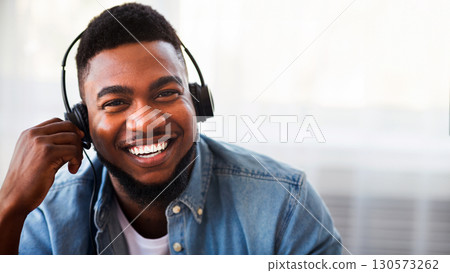 Call center operator. Portrait of smiling black customer service representative in headset, closeup 130573262