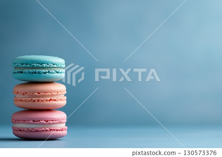 Colorful macarons stacked against a soft blue background creating a delightful dessert display 130573376