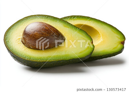 Freshly cut avocado halves showcasing vibrant green flesh and brown pit 130573417