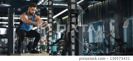 Crossfit athlete doing box jump exercise at gym, practicing functional training, empty space 130573431