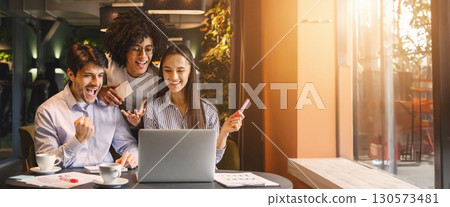 Coffee break meeting, e-learning and e-commerce activity concept. Successful multiethnic business team looking at laptop happily, working in cafe, free space 130573481