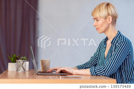 Serious Businesswoman Working On Laptop Typing Financial Report Sitting In Modern Office. Business Career Concept. Side View, Empty Space 130573489
