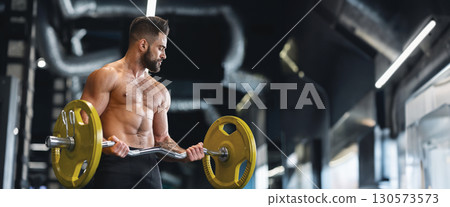 Handsome naked weightlifter lifting heavy barbell in gym, free space, panorama 130573573