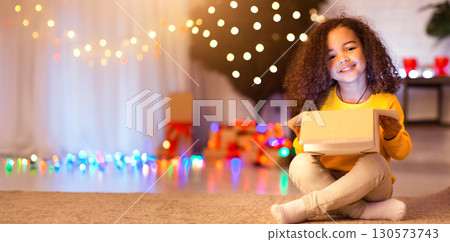 Christmas holidays. Happy african child enjoying gift near Xmas tree, free space 130573743