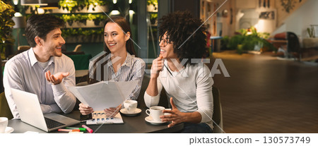 Young millennial multiethnic coworkers discussing papers during business lunch at cafe, copy space 130573749
