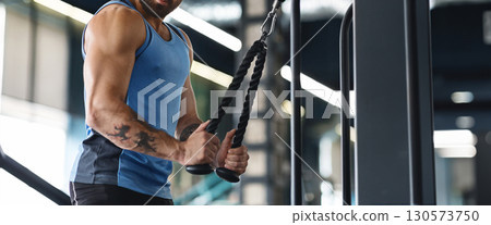 A muscular man with an athletic build exercises with weights in a contemporary gym, focusing on strength training in the morning, copy space A muscular man with an athletic build exercises with weights in a contemporary gym, focusing on strength training in the morning, copy space 130573750