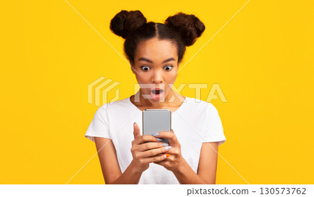 Human Reaction. Shocked african girl looking at phone seeing bad message. Panorama, free space Human Reaction. Shocked african girl looking at phone seeing bad message. Panorama, free space 130573762