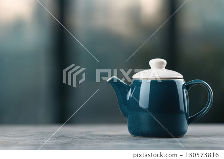 Elegant teal teapot placed on a rustic table with a blurred background showcasing a city view 130573816