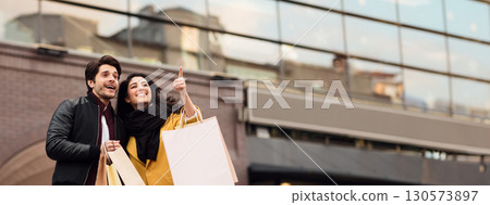 Millennial happy couple shopping together in new city, walking with paper bags and discovering city center, copy space Millennial happy couple shopping together in new city, walking with paper bags and discovering city center, copy space 130573897