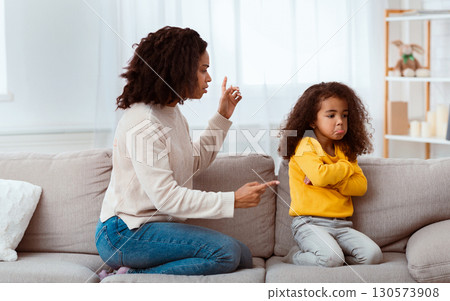 Angry Black Mother Scolding Kid Shouting At Sad Daughter Sitting On Sofa At Home. Family Quarrels And Problems Angry Black Mother Scolding Kid Shouting At Sad Daughter Sitting On Sofa At Home. Family Quarrels And Problems 130573908