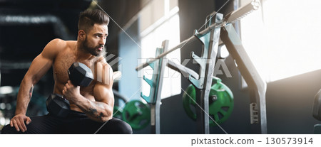 Strong muscular man with naked torso doing exercises with dumbbells, working out in gym, free space Strong muscular man with naked torso doing exercises with dumbbells, working out in gym, free space 130573914