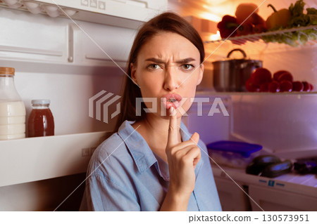 Don't bother me. Angry hungry woman opening fridge late, gesturing on camera Don't bother me. Angry hungry woman opening fridge late, gesturing on camera 130573951