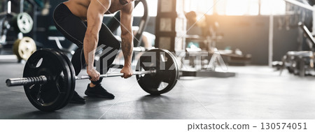 Hard strength workout. Muscular powerlifter lifting heavy barbell from gym floor, empty space, cropped 130574051