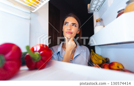 Lunch preparing problem. Thoughtful housewife looking into fridge, view from inside Lunch preparing problem. Thoughtful housewife looking into fridge, view from inside 130574414
