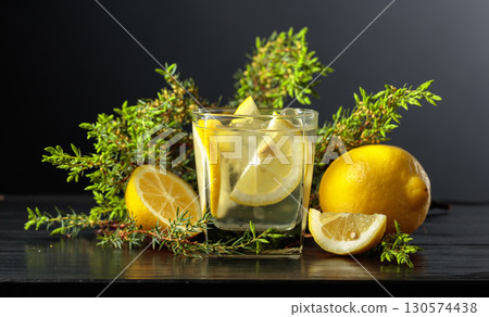 Cocktail Gin-tonic with ice, lemon, and juniper on a black background. Cocktail Gin-tonic with ice, lemon, and juniper on a black background. 130574438