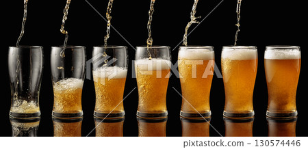 Pouring beer into a glass on a black background. 130574446