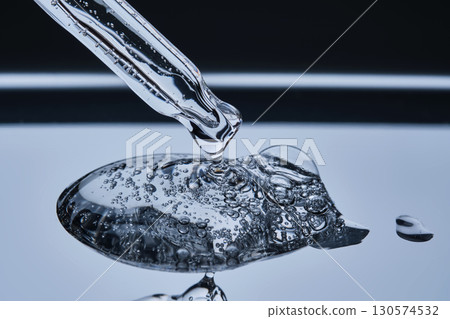 Hyaluronic serum drips from a pipette onto a steel tray. Hyaluronic serum drips from a pipette onto a steel tray. 130574532