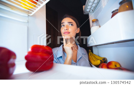 Pensive housewife looking into fridge at kitchen, view from inside 130574542