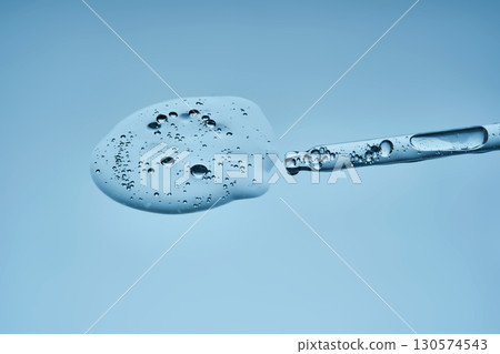 A pipette with hyaluronic serum on a blue background. 130574543