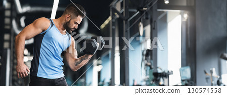 Muscular sportsman with strong body lifting heavy dumbbell, empty space, web-banner 130574558