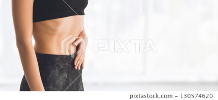 A young woman is performing a yoga pose with hands in prayer position, illuminated by gentle morning light, cropped, copy space 130574620