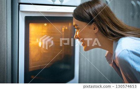 Stay at home. Happy woman looking into oven showcase at cooking lunch, free space 130574653