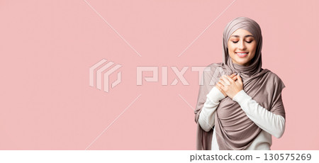 Gratitude concept. Thankful muslim girl in hijab keeping both palms on chest, expressing appreciation over pink studio background with copy space Gratitude concept. Thankful muslim girl in hijab keeping both palms on chest, expressing appreciation over pink studio background with copy space 130575269