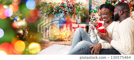 Romantic black couple celebrating Christmas with hot winter cocoa, holding cups and bonding near Xmas tree at home. Romantic black couple celebrating Christmas with hot winter cocoa, holding cups and bonding near Xmas tree at home. 130575464