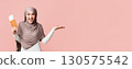 Portrait of euphoric arabic woman in hijab with passport and boarding tickets pointing aside with her open palm, demonstrating invisible object, copy space 130575542