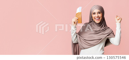 Time To Travel. Joyful arabic woman in hijab holding passport with boarding passes and raising hands in excitement, pink background with copy space Time To Travel. Joyful arabic woman in hijab holding passport with boarding passes and raising hands in excitement, pink background with copy space 130575546